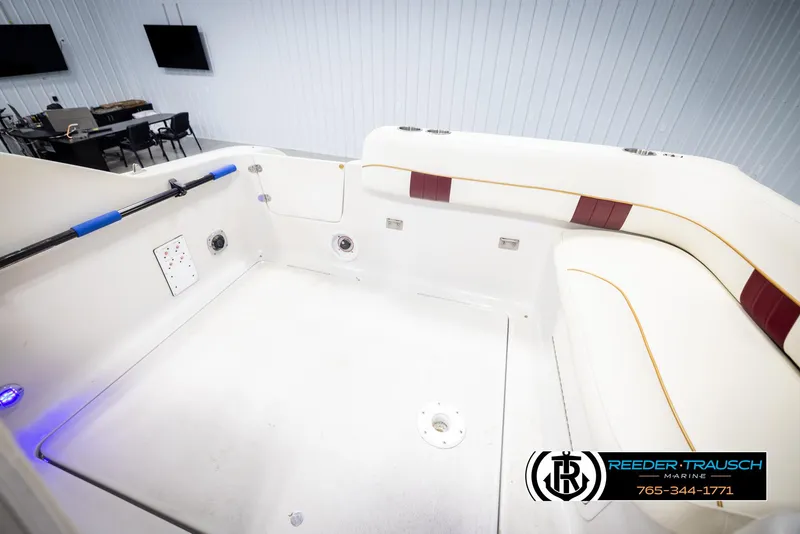 Slide: The Image of 1999 Crownline 242 CR boat interior with white and maroon seating, spacious layout. - 24