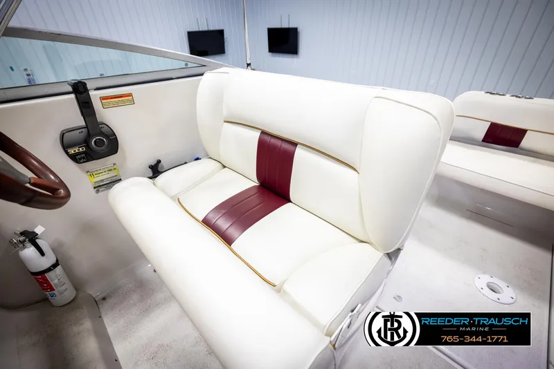 Slide: The Image of 1999 Crownline 242 CR boat interior with white and maroon seating, steering wheel, and fire extinguisher. - 30