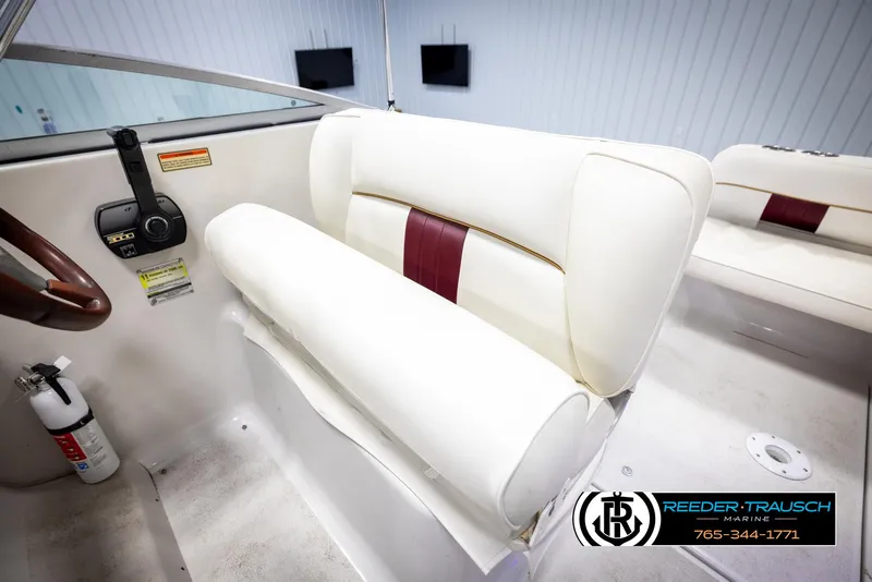 Slide: The Image of 1999 Crownline 242 CR boat interior with white and maroon seating, steering wheel, and controls. - 31