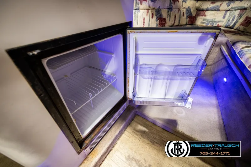 Slide: The Image of 1999 Crownline 242 CR boat interior with open mini fridge and seating area. - 42