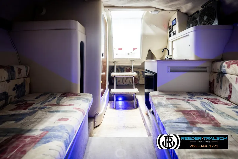 Slide: The Image of Interior of 1999 Crownline 242 CR boat with seating, kitchenette, and ambient lighting. - 47