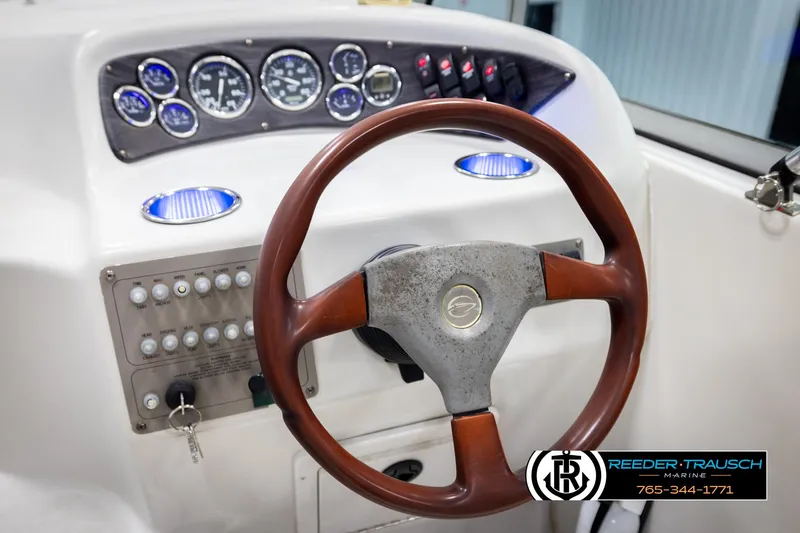 Slide: The Image of 1999 Crownline 242 CR boat dashboard with wood steering wheel and instrument panel. - 49