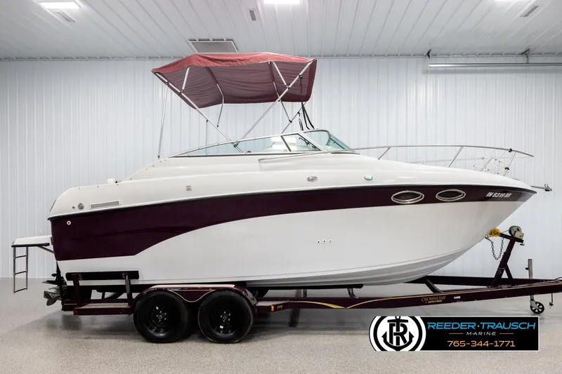 Slide: The Image of 1999 Crownline 242 CR boat with maroon accents on a trailer in a showroom. - 5