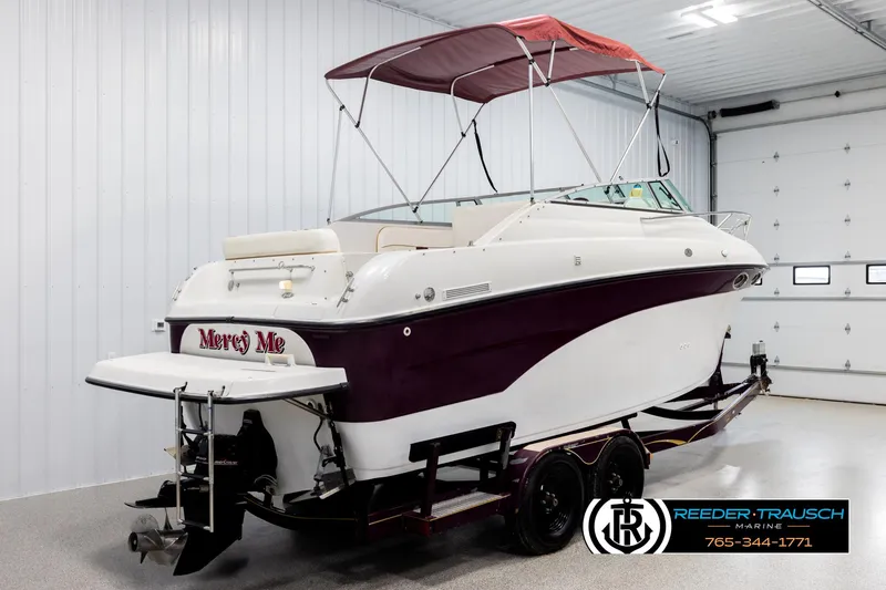 Slide: The Image of 1999 Crownline 242 CR boat with maroon accents in a garage setting. - 6