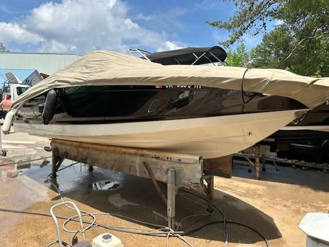 The Image of 2011 Chaparral 216 SSi boat covered and elevated on a stand outdoors. - 1