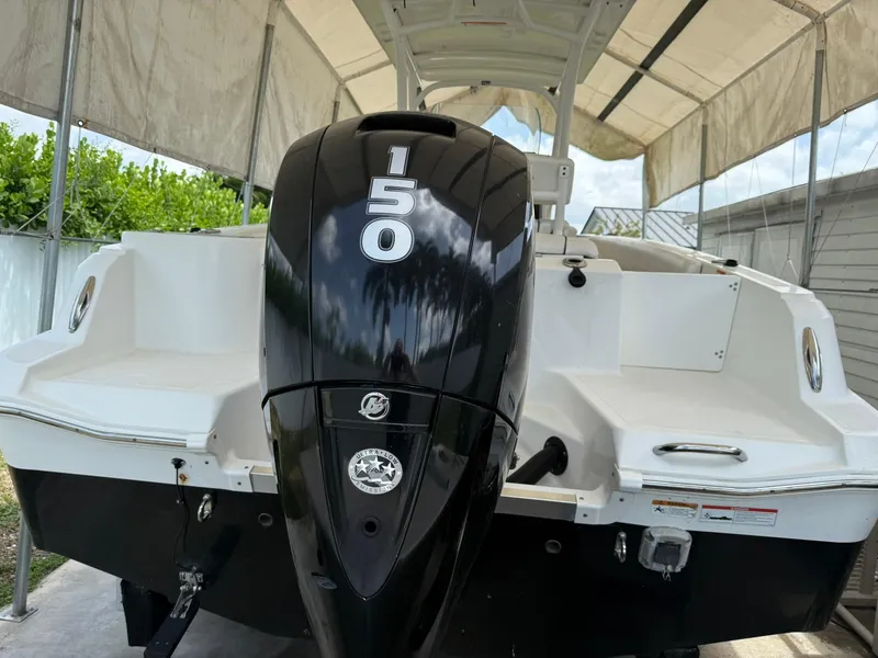 Slide: The Image of 2020 Wellcraft 222 Fisherman boat with 150 horsepower engine, docked under a canopy. - 13