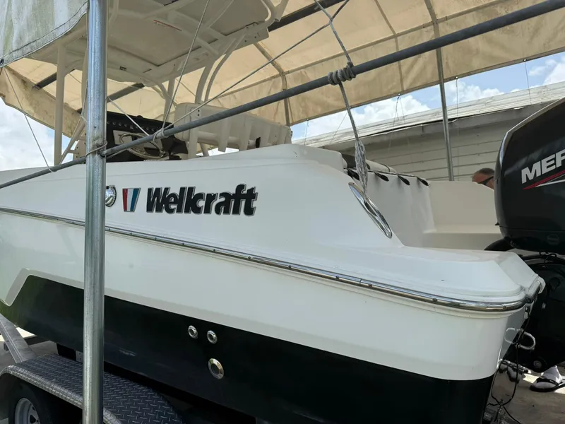 Slide: The Image of 2020 Wellcraft 222 Fisherman boat on trailer under canopy, featuring a Mercury engine. - 5