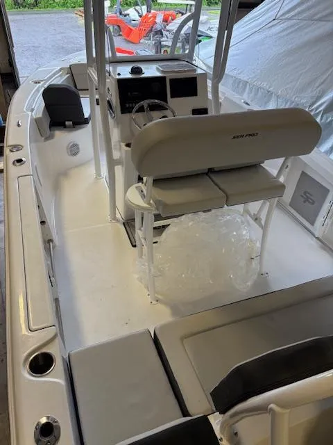 Slide: The Image of 2025 Sea Pro 225 Sandbar boat interior with seating and console in a garage setting. - 15