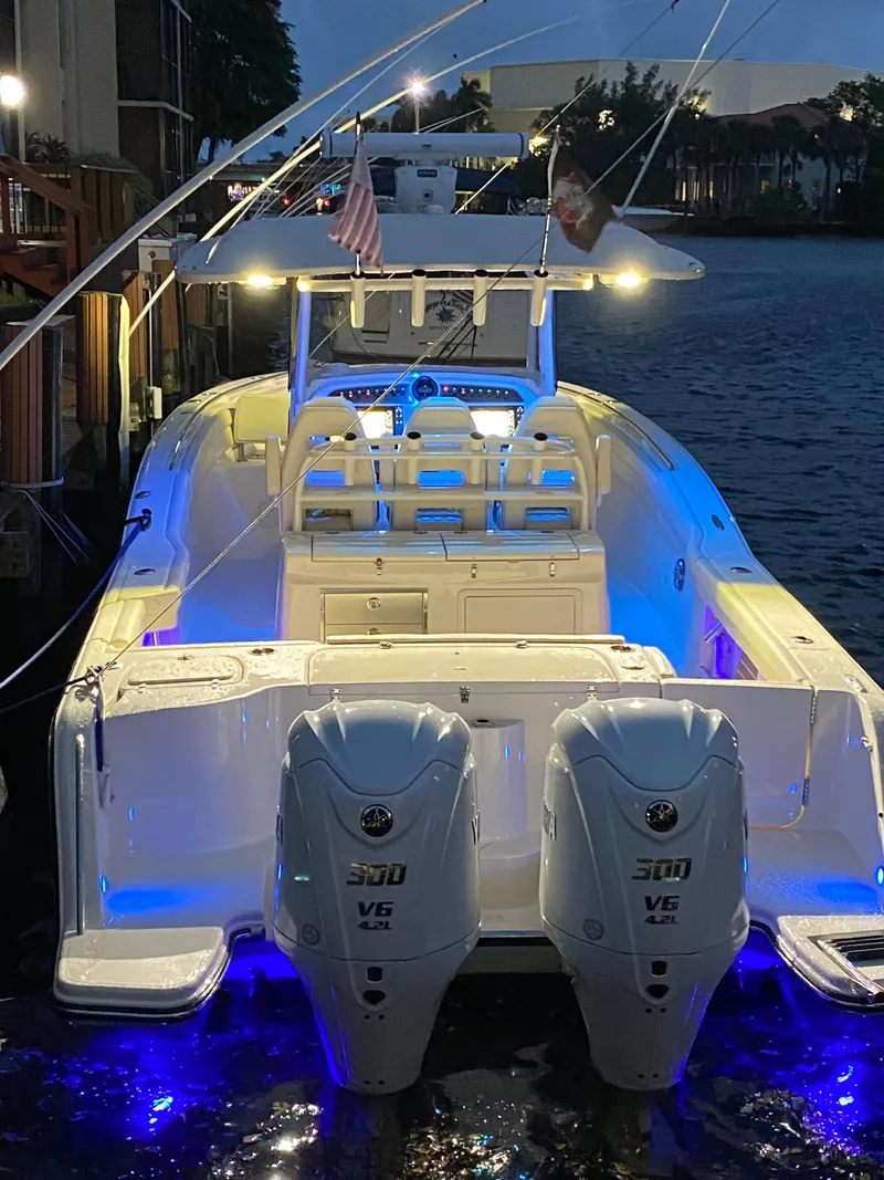 Slide: The Image of 2024 Grady-White Canyon 326 boat with dual engines, illuminated at night by blue lights. - 1