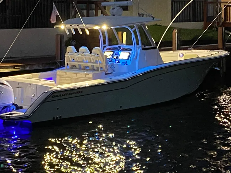 Slide: The Image of 2024 Grady-White Canyon 326 boat illuminated at night, docked on calm water. - 2