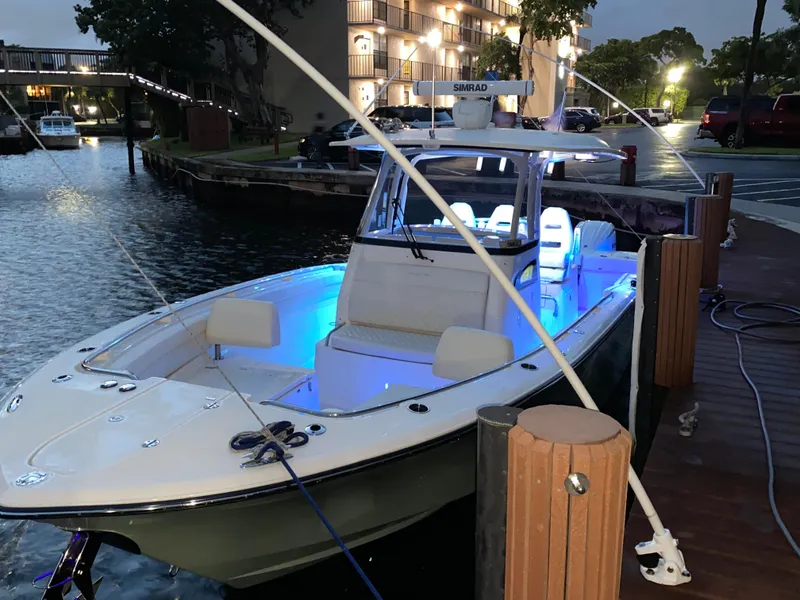 Slide: The Image of 2024 Grady-White Canyon 326 boat docked, illuminated with blue interior lights at dusk. - 3