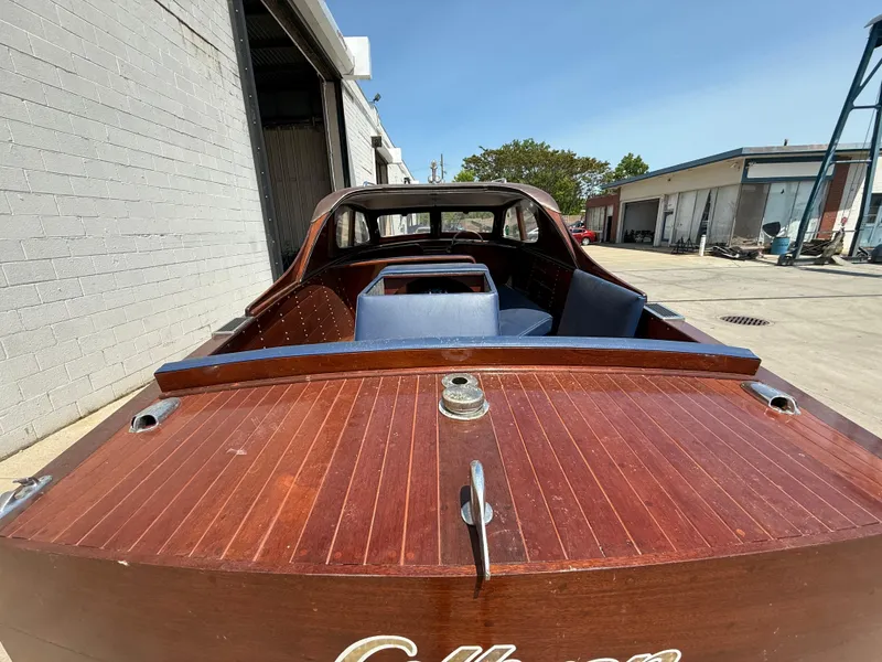 Slide: The Image of 1950 Chris-Craft 22' Custom Sedan with wooden deck, parked outdoors near industrial buildings. - 15
