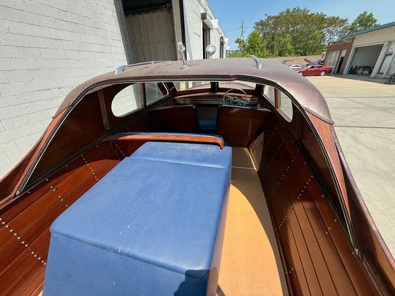 Slide: The Image of 1950 Chris-Craft 22' Custom Sedan with wooden interior and blue seating, parked outdoors. - 3