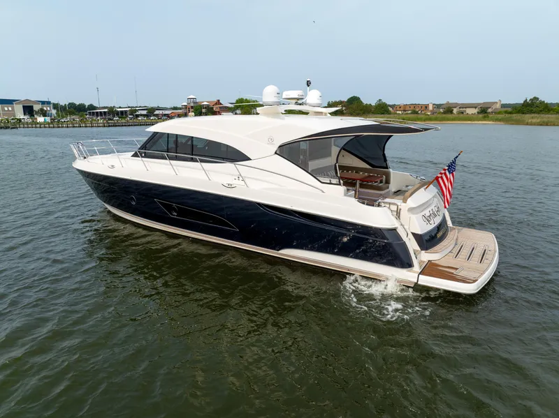 Slide: The Image of 2018 Riviera 5400 Sport Yacht cruising on calm waters, featuring sleek design and American flag. - 0