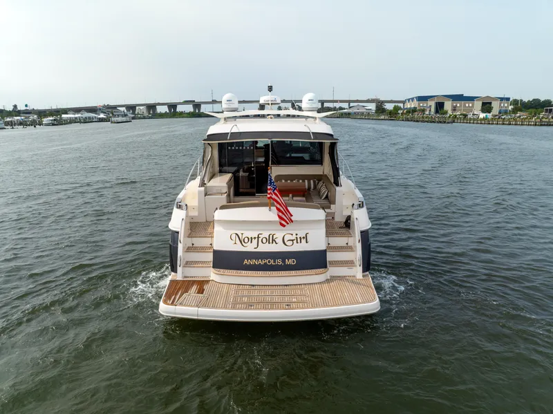 Slide: The Image of 2018 Riviera 5400 Sport Yacht cruising in open water, rear view with American flag. - 1