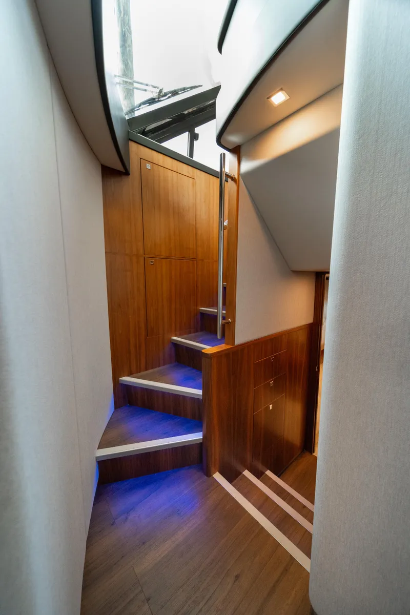 Slide: The Image of 2018 Riviera 5400 Sport Yacht interior staircase with modern wood finish and ambient lighting. - 20