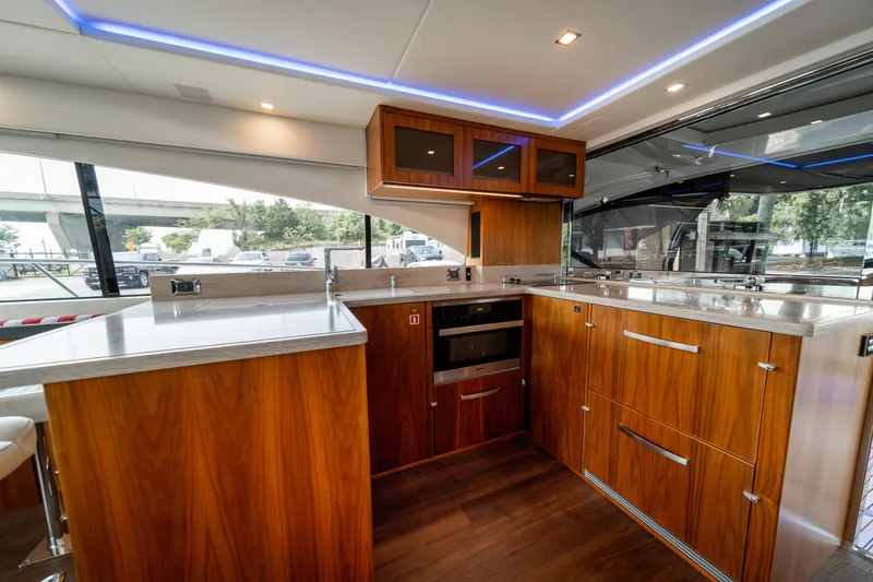 Slide: The Image of Luxurious 2018 Riviera 5400 Sport Yacht kitchen with sleek wood cabinetry and modern appliances. - 37