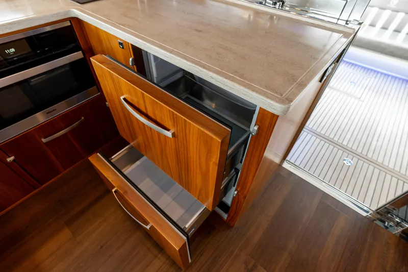 Slide: The Image of Luxurious 2018 Riviera 5400 Sport Yacht kitchen with wooden cabinetry and modern appliances. - 42