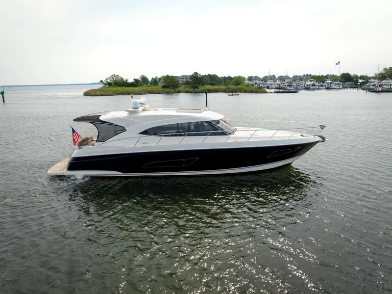 Slide: The Image of 2018 Riviera 5400 Sport Yacht cruising on calm waters near a marina. - 6