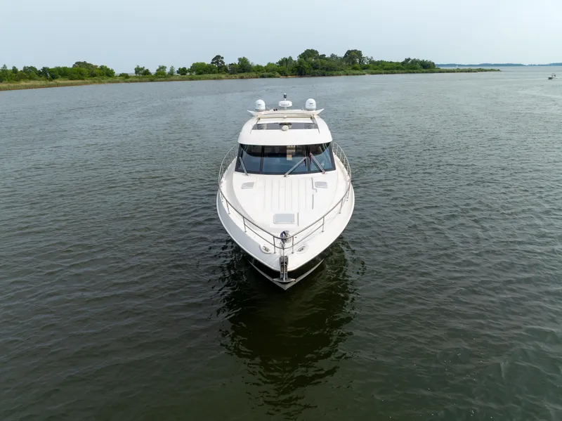 Slide: The Image of 2018 Riviera 5400 Sport Yacht cruising on calm waters, surrounded by lush greenery. - 8
