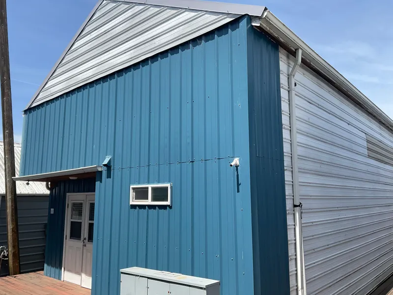 The Image of Blue and white custom boathouse, 1980, with metal siding and small window. - 1