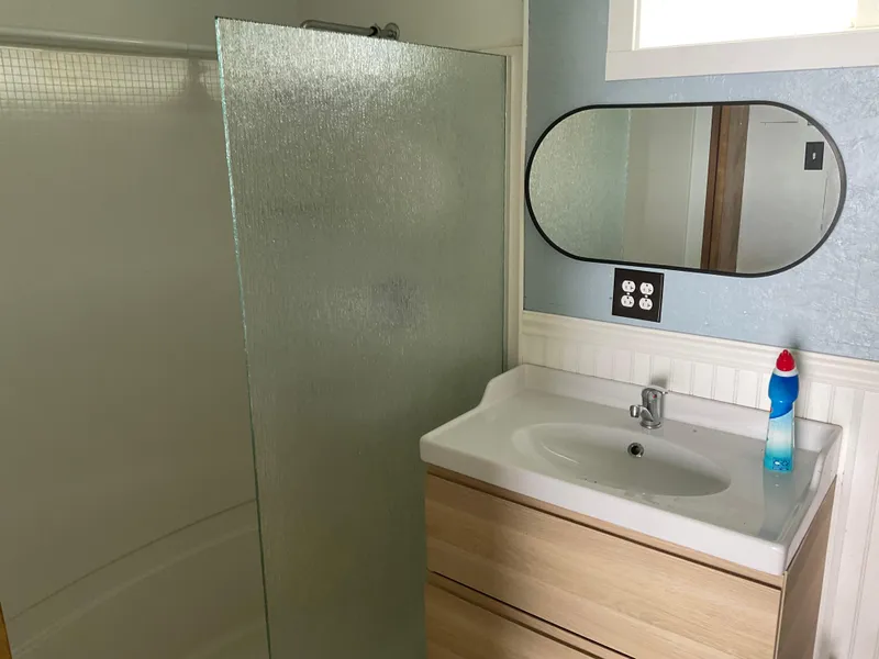 Slide: The Image of Modern bathroom with glass shower, wooden vanity, and oval mirror in a 1980 Custom Boathouse. - 7