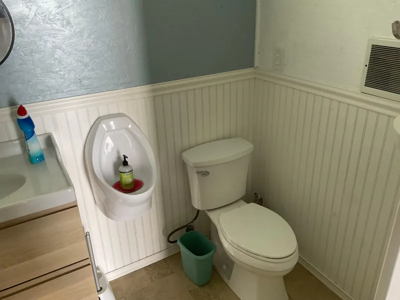 Slide: The Image of Small bathroom with toilet, urinal, and sink in a 1980 custom boathouse. - 8