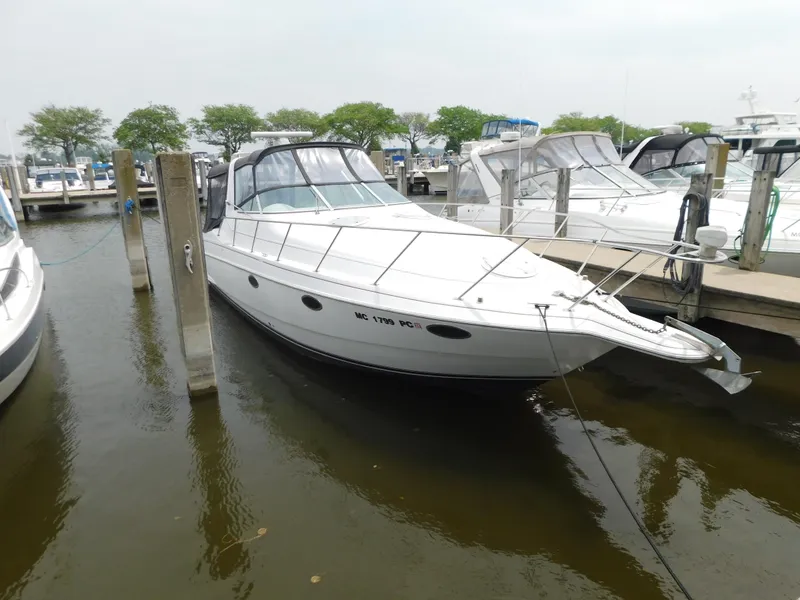 The Image of 1991 Chris-Craft 302 Crowne boat docked at marina, white exterior, calm water. - 1