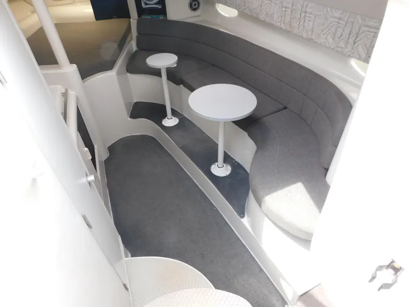 Slide: The Image of 1991 Chris-Craft 302 Crowne interior with gray seating and two small tables. - 12