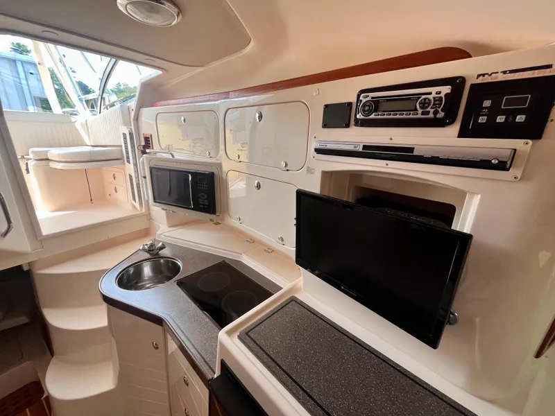 Slide: The Image of 2007 Grady-White Express 330 interior with kitchenette, sink, microwave, and TV. - 12