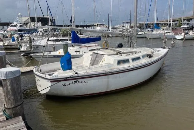The Image of 1977 Catalina 30 Tall Rig sailboat docked in a marina, surrounded by other boats. - 1