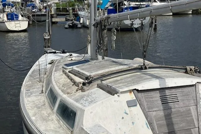 Slide: The Image of 1977 Catalina 30 Tall Rig sailboat docked in a marina, showing weathered deck and mast. - 4