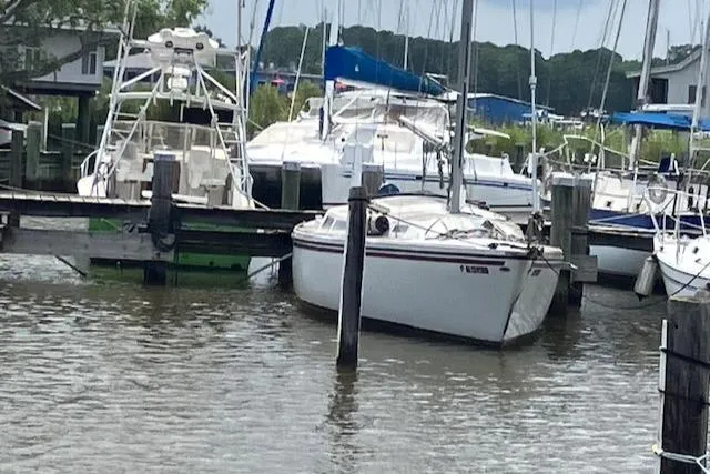 Slide: The Image of 1977 Catalina 30 Tall Rig sailboat docked in a marina, surrounded by other boats. - 5