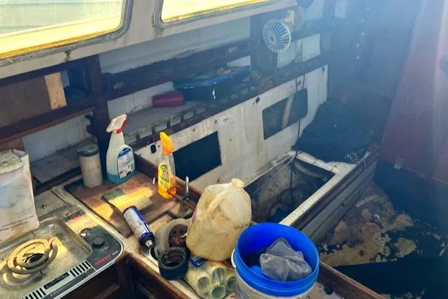 Slide: The Image of Interior of a 1977 Catalina 30 Tall Rig sailboat, showing cluttered and worn kitchen area. - 6