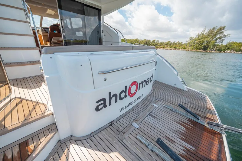 Slide: The Image of Luxury Princess F54 yacht deck with wooden flooring, docked near lush shoreline. - 97