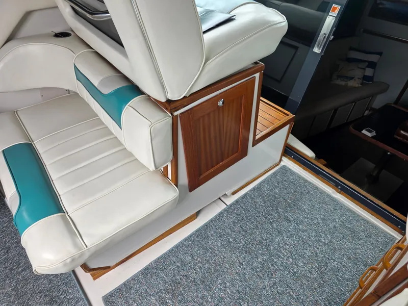 Slide: The Image of 1987 Sea Ray 390 Express Cruiser interior with white and teal seating, wooden accents. - 10