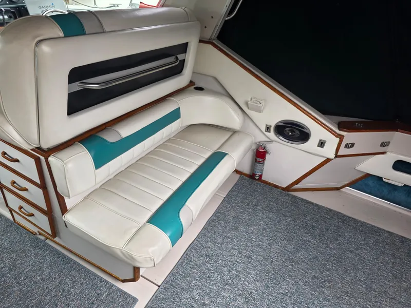 Slide: The Image of 1987 Sea Ray 390 Express Cruiser interior with white and teal seating, carpet, and storage drawers. - 14