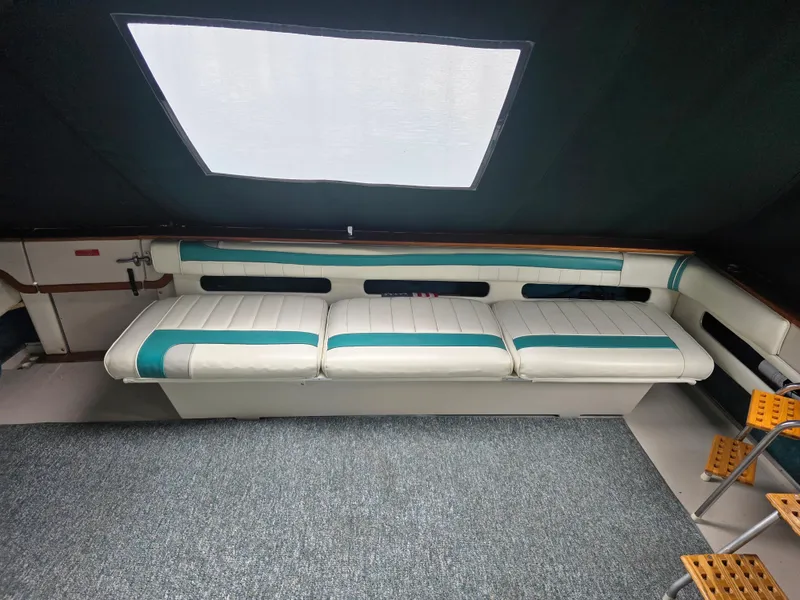 Slide: The Image of 1987 Sea Ray 390 Express Cruiser interior with white and teal seating, carpeted floor, and large window. - 15