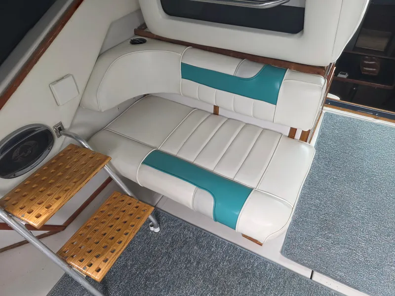 Slide: The Image of 1987 Sea Ray 390 Express Cruiser interior with white and teal seating, wooden steps, and carpeted floor. - 22