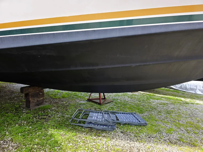 Slide: The Image of 1987 Sea Ray 390 Express Cruiser hull on stands, with tools on grass. - 42
