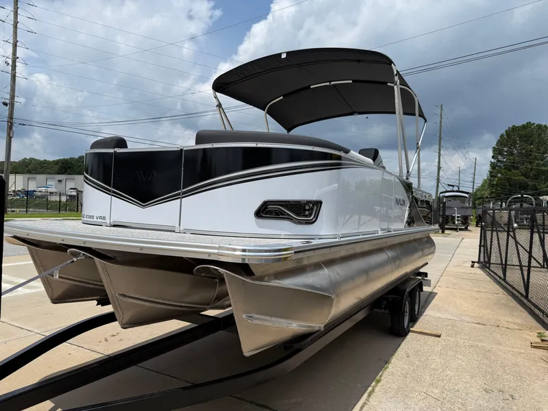 Slide: The Image of 2025 Avalon LSZ Versatile Rear Bench pontoon boat on trailer, under cloudy sky. - 3