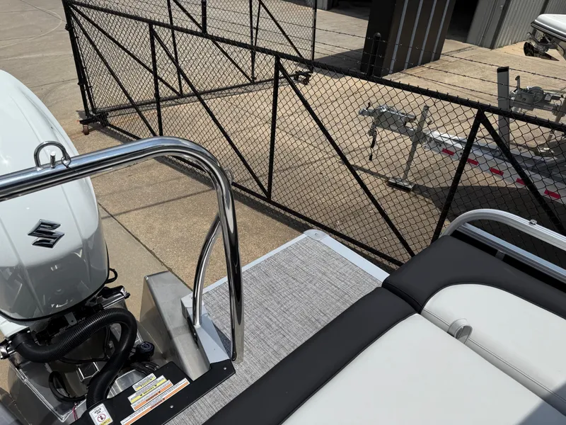 Slide: The Image of 2025 Avalon LSZ Versatile Rear Bench boat with Suzuki engine, docked near a metal fence. - 37