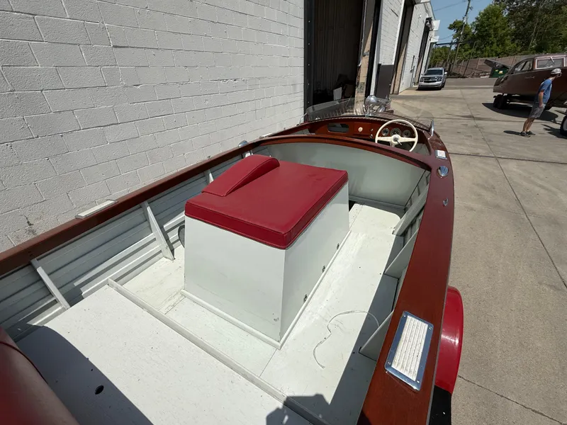 Slide: The Image of 1953 Chris-Craft 17’ Sportsman boat with red seating, parked outside a garage. - 12
