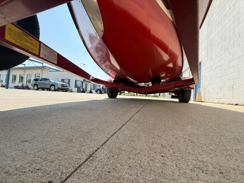 Slide: The Image of 1953 Chris-Craft 17’ Sportsman boat on trailer, viewed from below, showcasing red hull. - 17