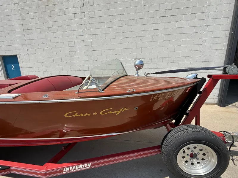 Slide: The Image of 1953 Chris-Craft 17’ Sportsman boat on trailer, classic wooden design, parked outdoors. - 4