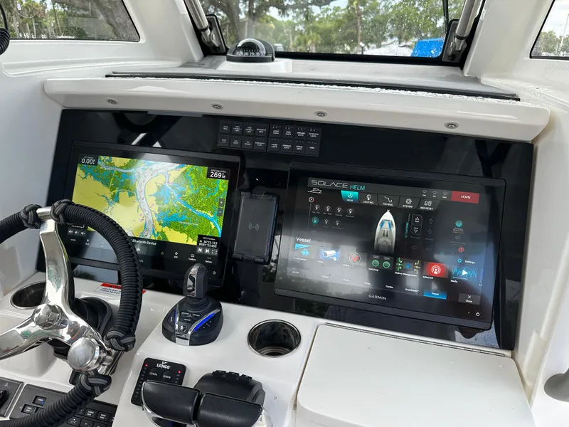 Slide: The Image of 2024 Solace 32 CS boat interior with seating and storage, on calm water. - 17