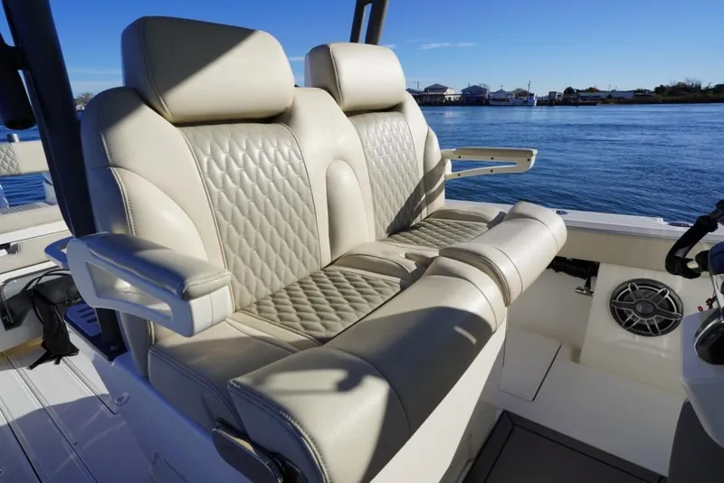 Slide: The Image of Luxurious seating on 2024 Solace 32 CS boat, featuring quilted upholstery and armrests, with scenic water view. - 26