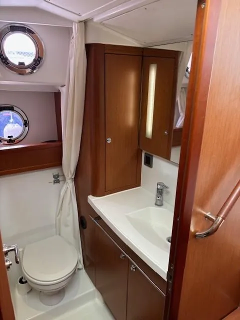 Slide: The Image of 2014 Beneteau Swift Trawler 44 bathroom with wooden cabinets and porthole windows. - 25
