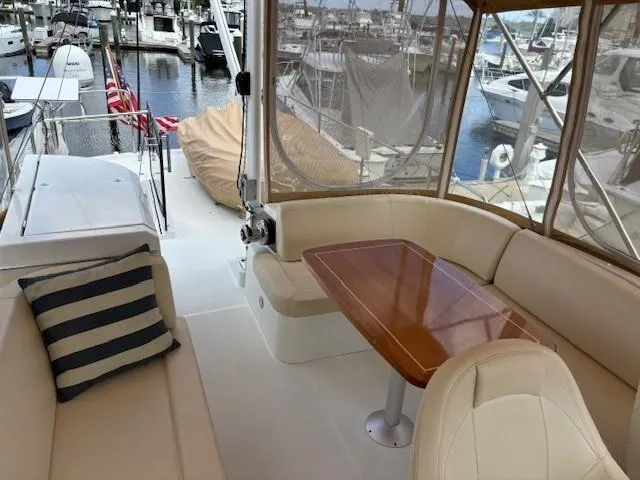 Slide: The Image of 2014 Beneteau Swift Trawler 44 with elegant seating and wooden table in marina setting. - 4