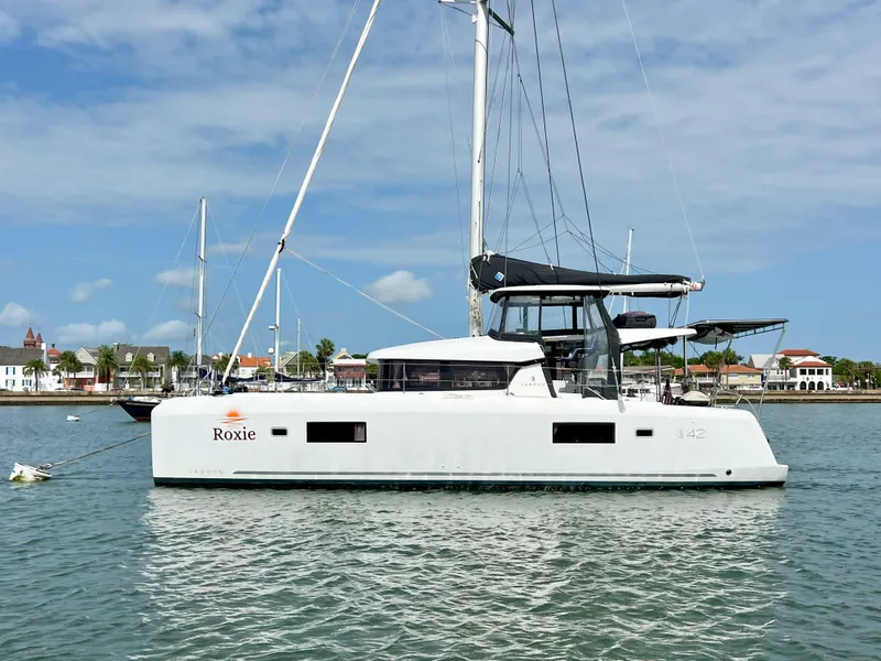 Slide: The Image of 2024 Lagoon 42 catamaran sailing on calm waters under a clear blue sky. - 1